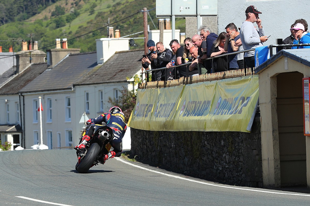 A motorcyclist races past houses at a speed of 300 km/h.