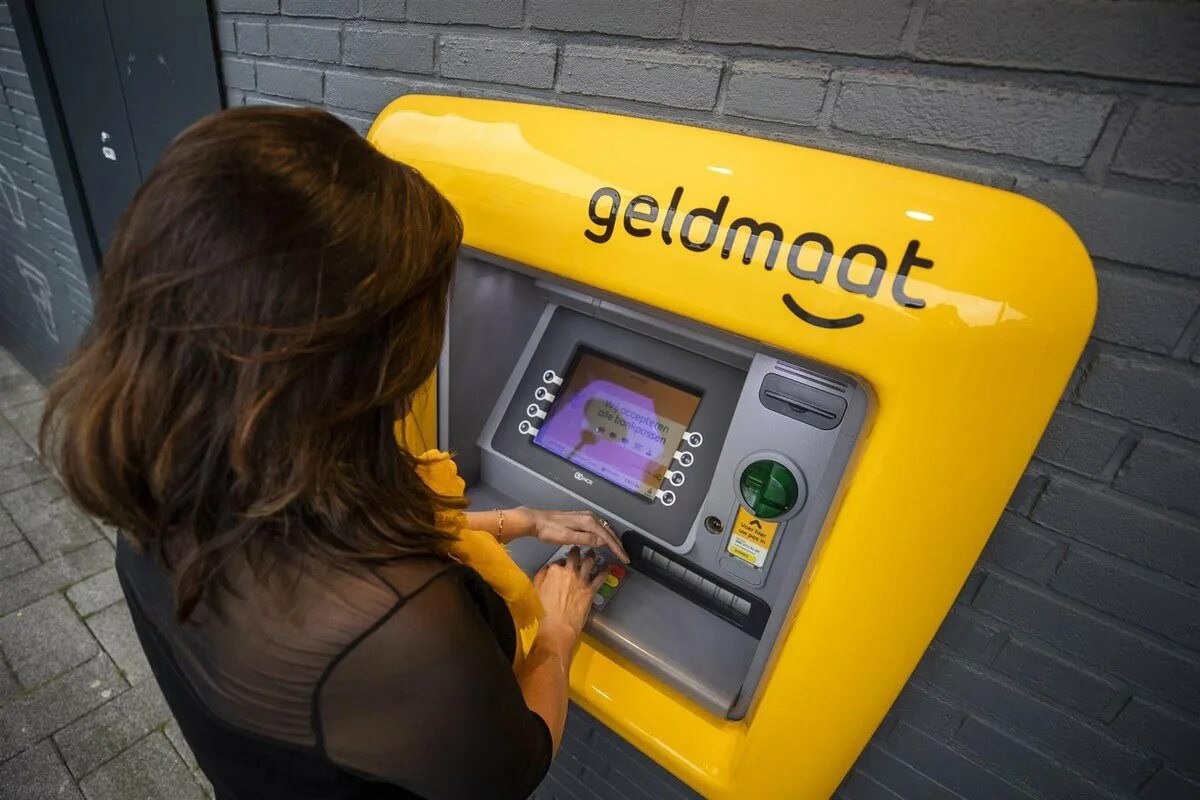 Een meisje voert haar pincode in bij een geldautomaat