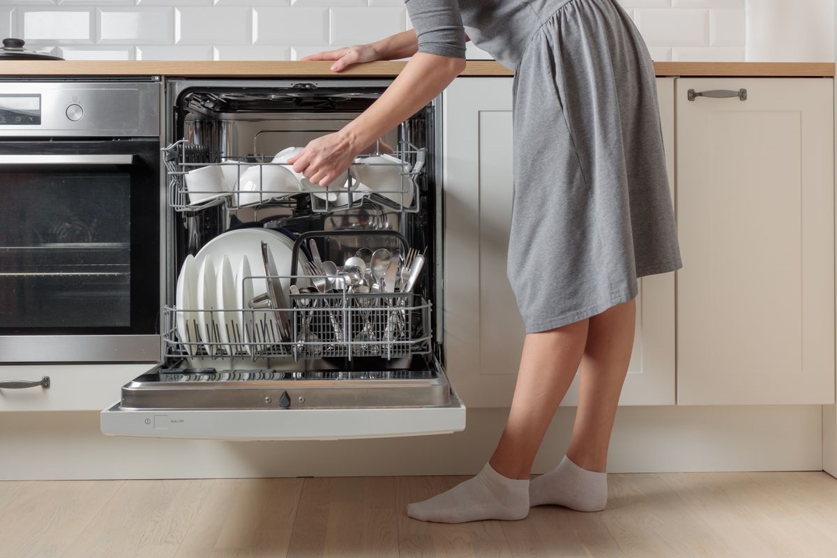 Een meisje zet glazen in de vaatwasser